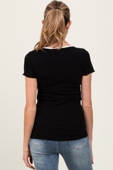 woman wearing a black maternity top with short sleeves, shown from the back, paired with light blue jeans