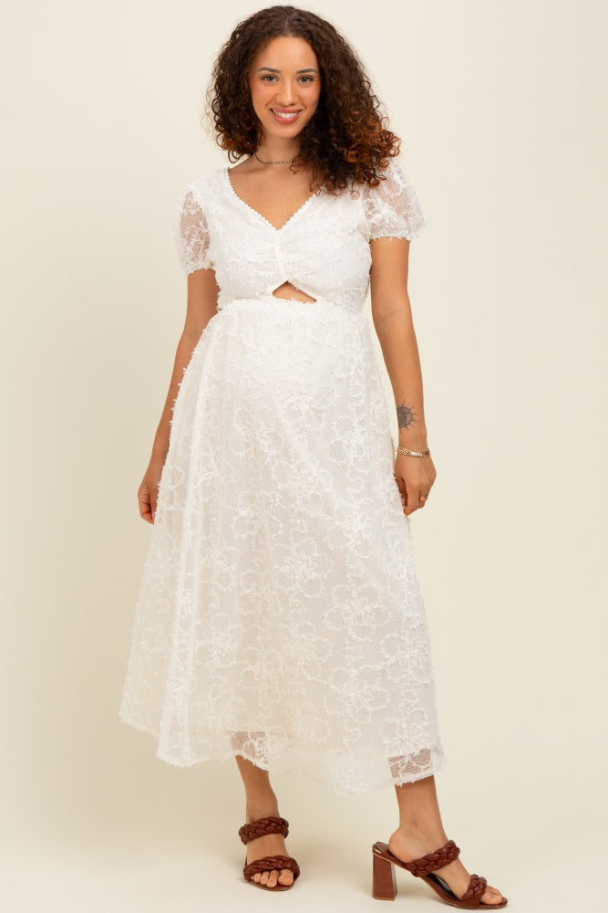 woman wearing a white lace maternity dress with short puff sleeves and a keyhole cutout, showcasing her baby bump