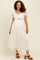 woman wearing a white lace maternity dress with short puff sleeves and a keyhole cutout, showcasing her baby bump