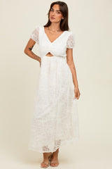 woman wearing a white lace maxi dress with puff sleeves and a cut-out detail at the waist