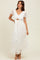 woman wearing a white lace maxi dress with puff sleeves and a cut-out detail at the waist