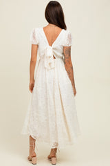 woman wearing a white lace maxi dress with a back tie detail and short puff sleeves