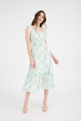 woman wearing a green and white floral midi dress with ruffled straps and a tiered skirt