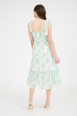 woman wearing a flowy green floral midi dress with adjustable tie straps and a tiered hem, shown from the back