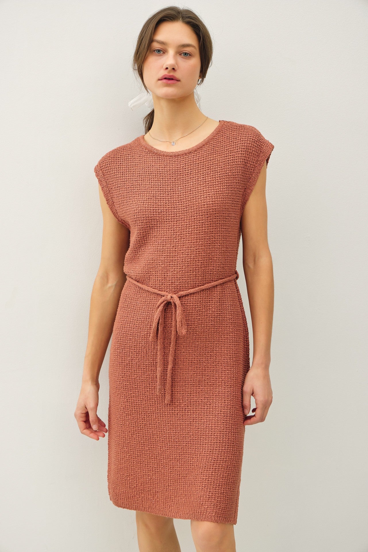woman wearing a rose-colored knit dress with short sleeves and a tie belt at the waist