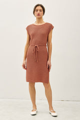 woman wearing a rust-colored knit dress with short sleeves and a tie waist detail