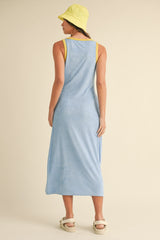 woman wearing a light blue sleeveless maxi dress with yellow accents and a yellow bucket hat, standing from the back