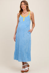 woman wearing a light blue maternity maxi dress with yellow accents and pockets, showcasing her baby bump