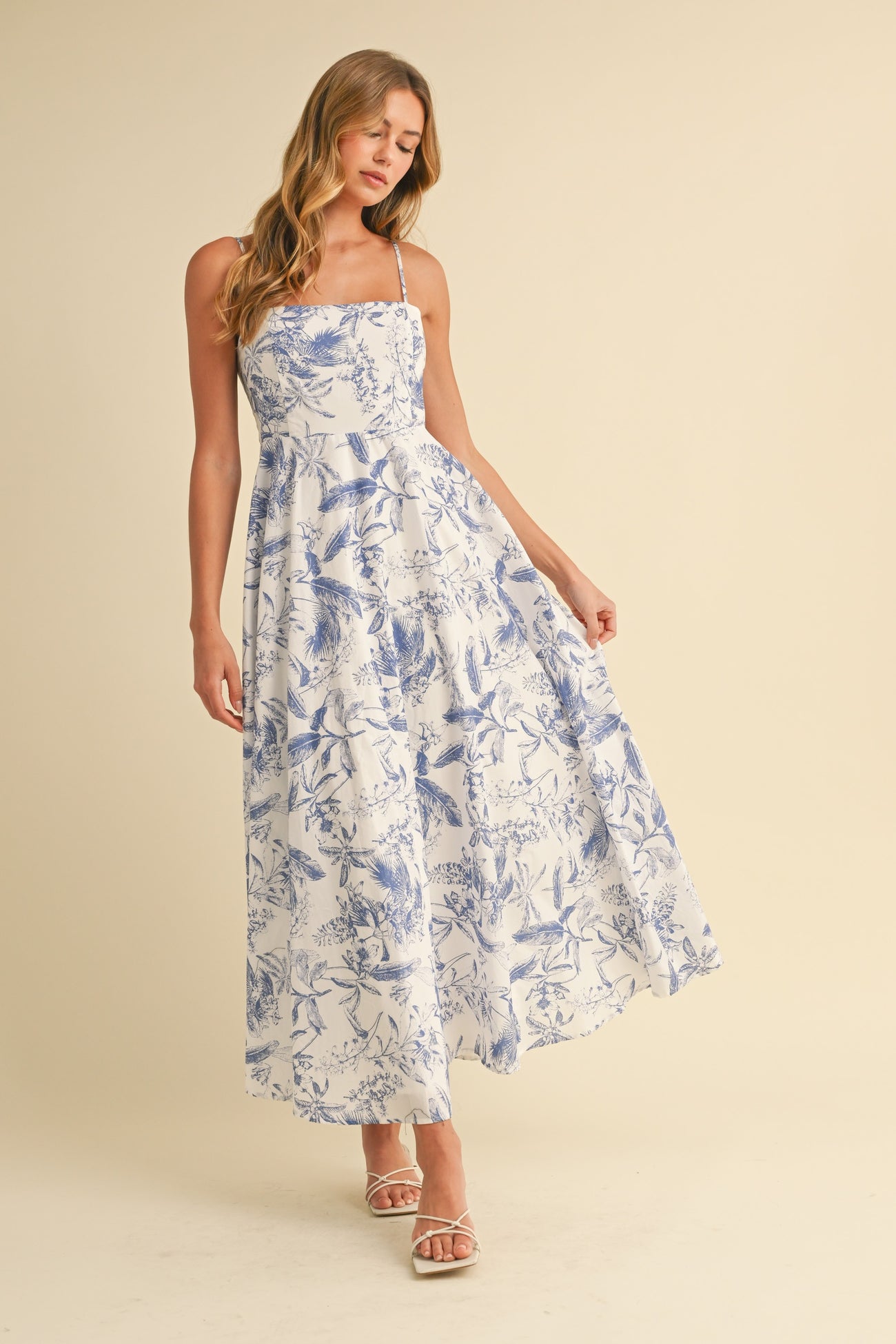woman wearing a white floral maxi dress with blue patterns and thin straps