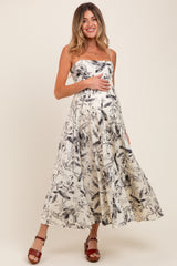woman wearing a strapless black and white floral maternity dress and holding her baby bump