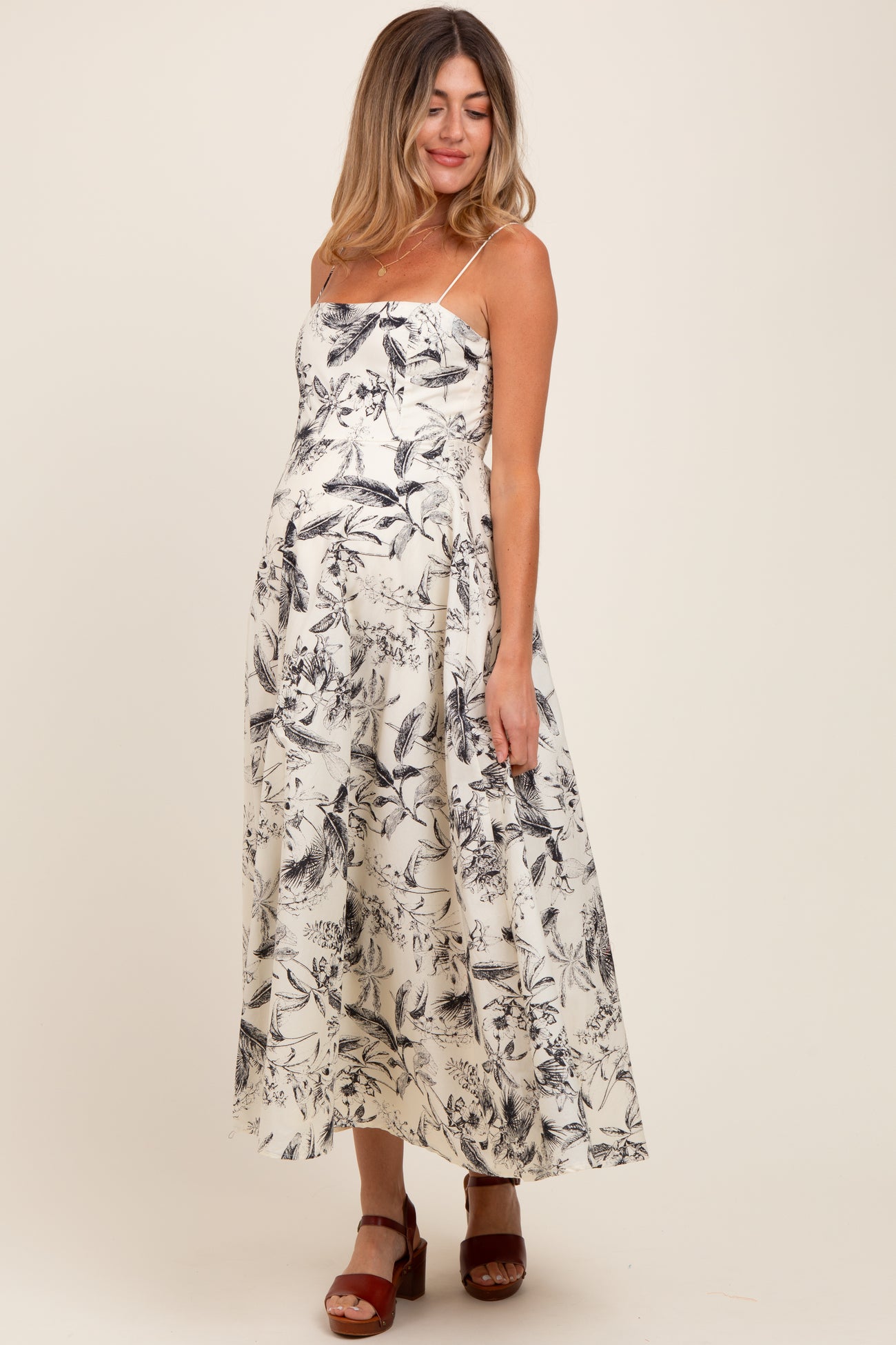 woman wearing a black and white floral print maternity dress with spaghetti straps and a visible baby bump