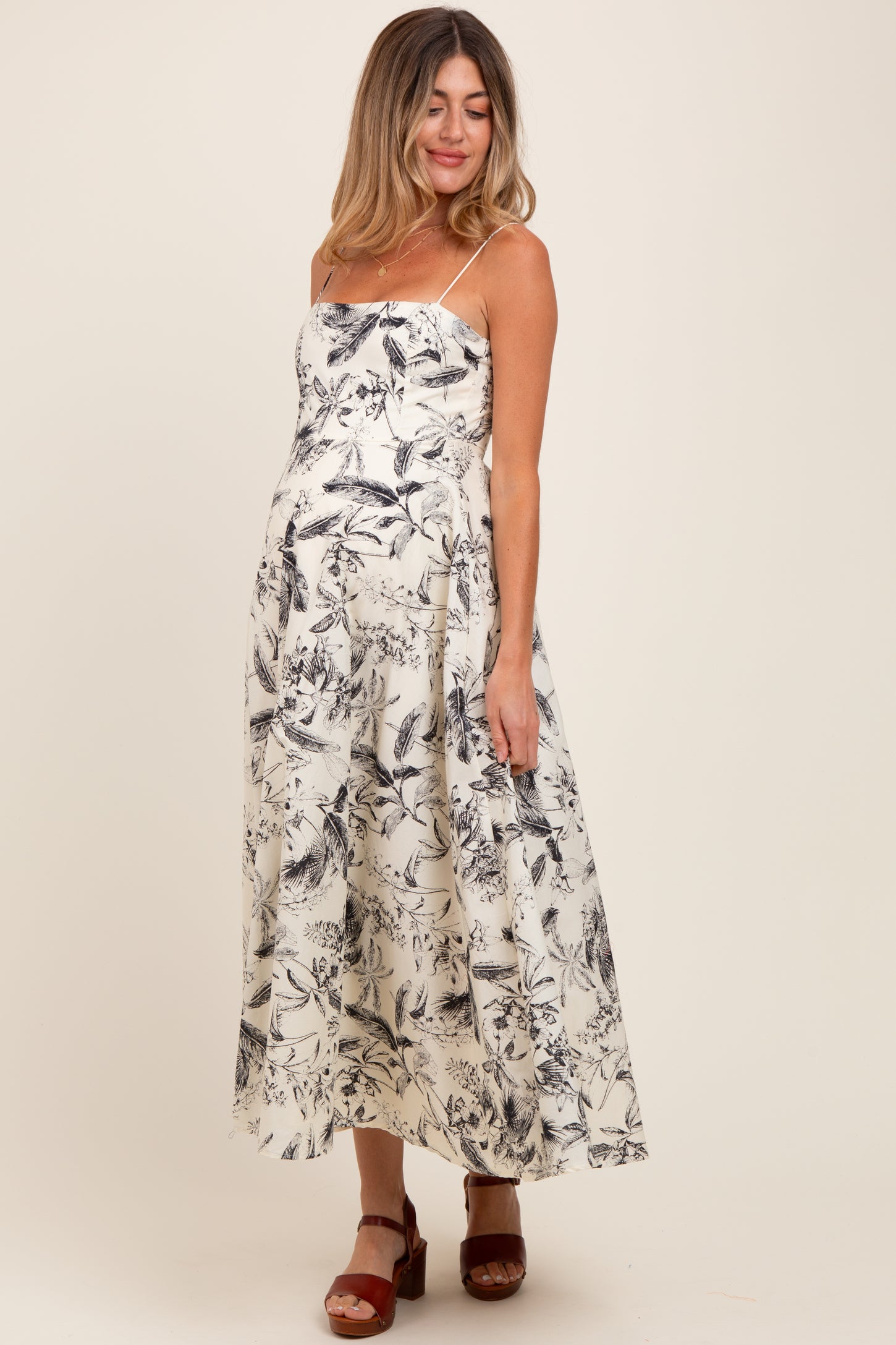 woman wearing a black and white floral print maternity dress with spaghetti straps and a visible baby bump