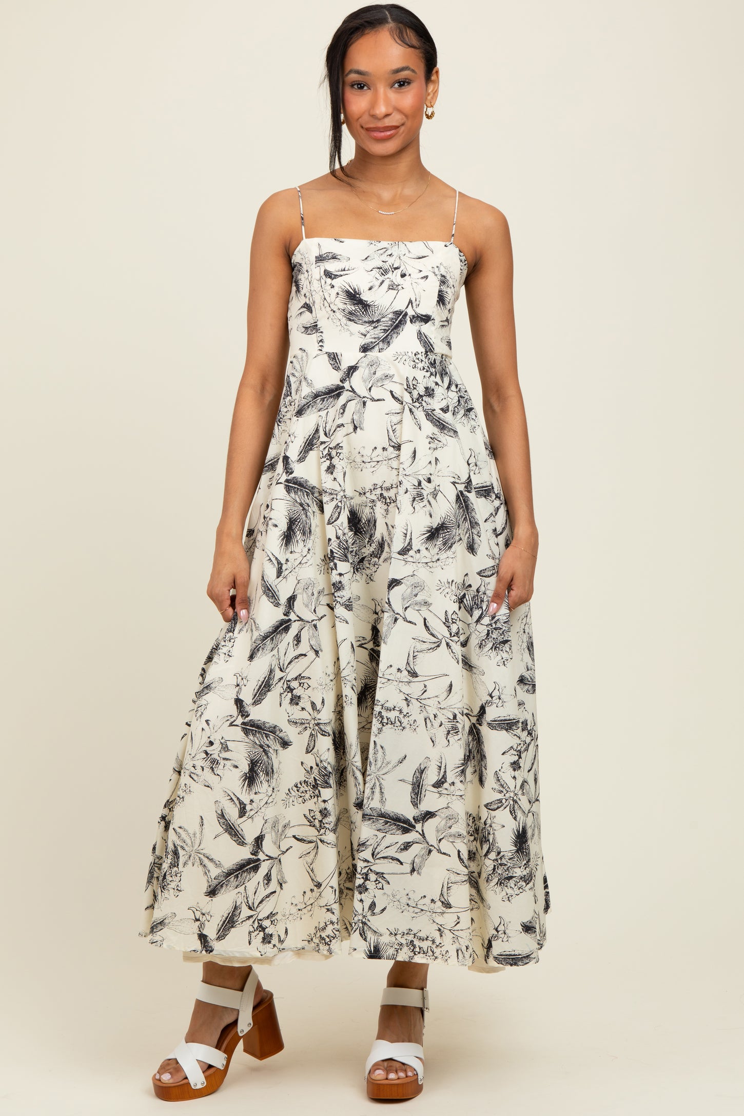 woman wearing a floral print maxi dress with spaghetti straps and a flowy silhouette