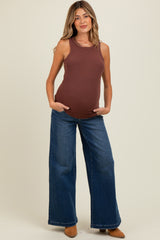 woman wearing a brown ribbed maternity tank top and loose blue jeans, showing her baby bump
