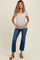 woman wearing a light beige short sleeve maternity top and blue flared jeans, holding her baby bump