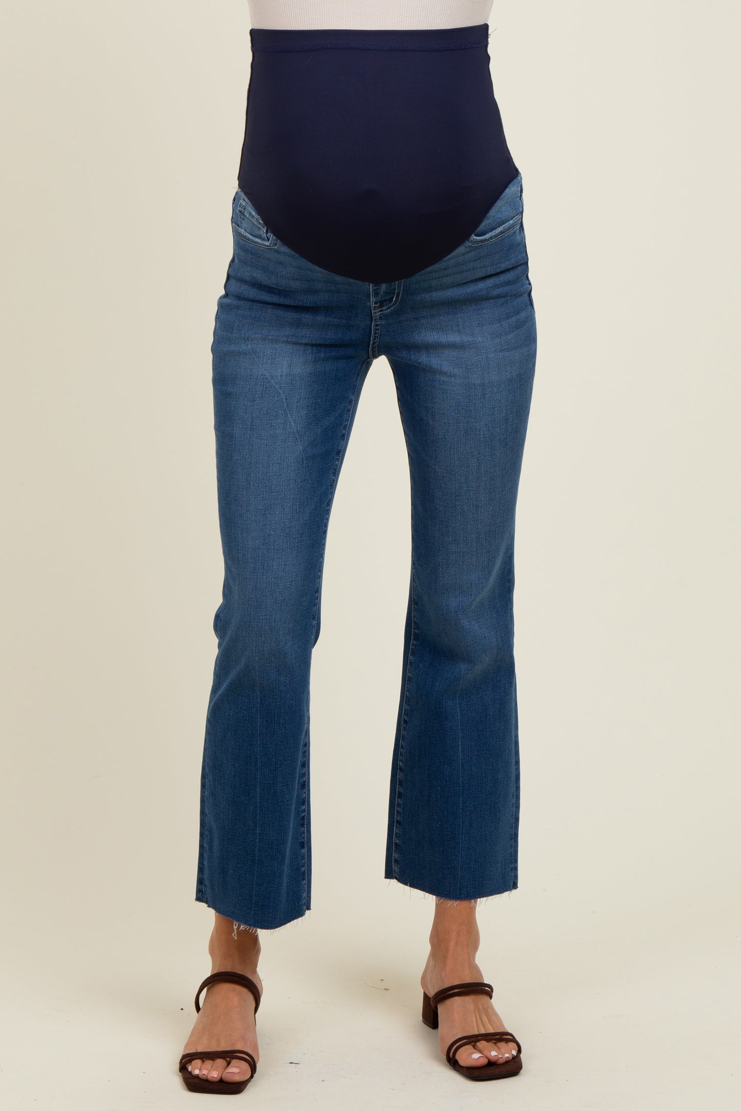 woman wearing a pair of dark blue maternity jeans with a high waistband and cropped flared hem