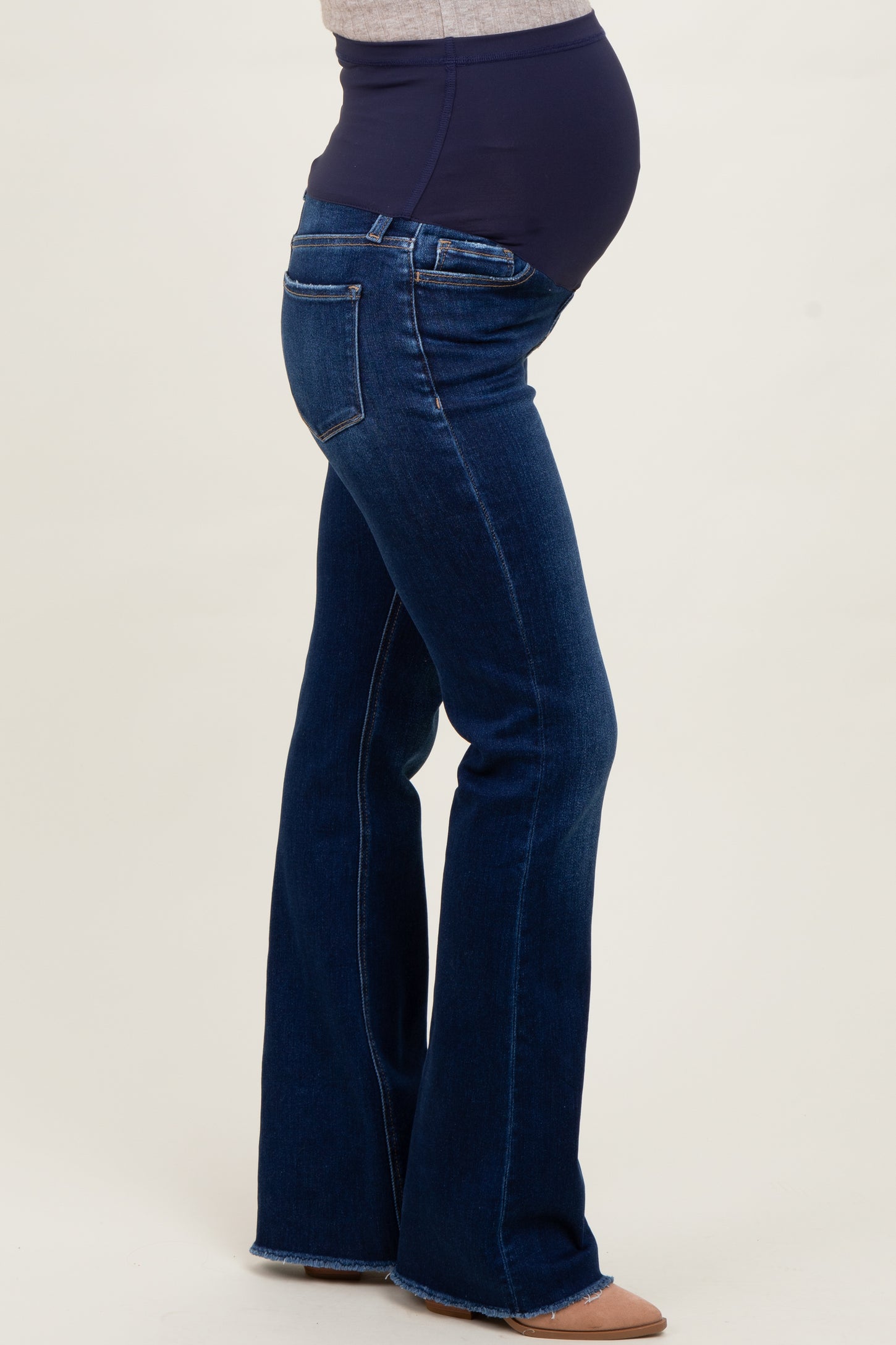 woman wearing dark blue maternity flared jeans featuring a supportive waistband and showing her baby bump