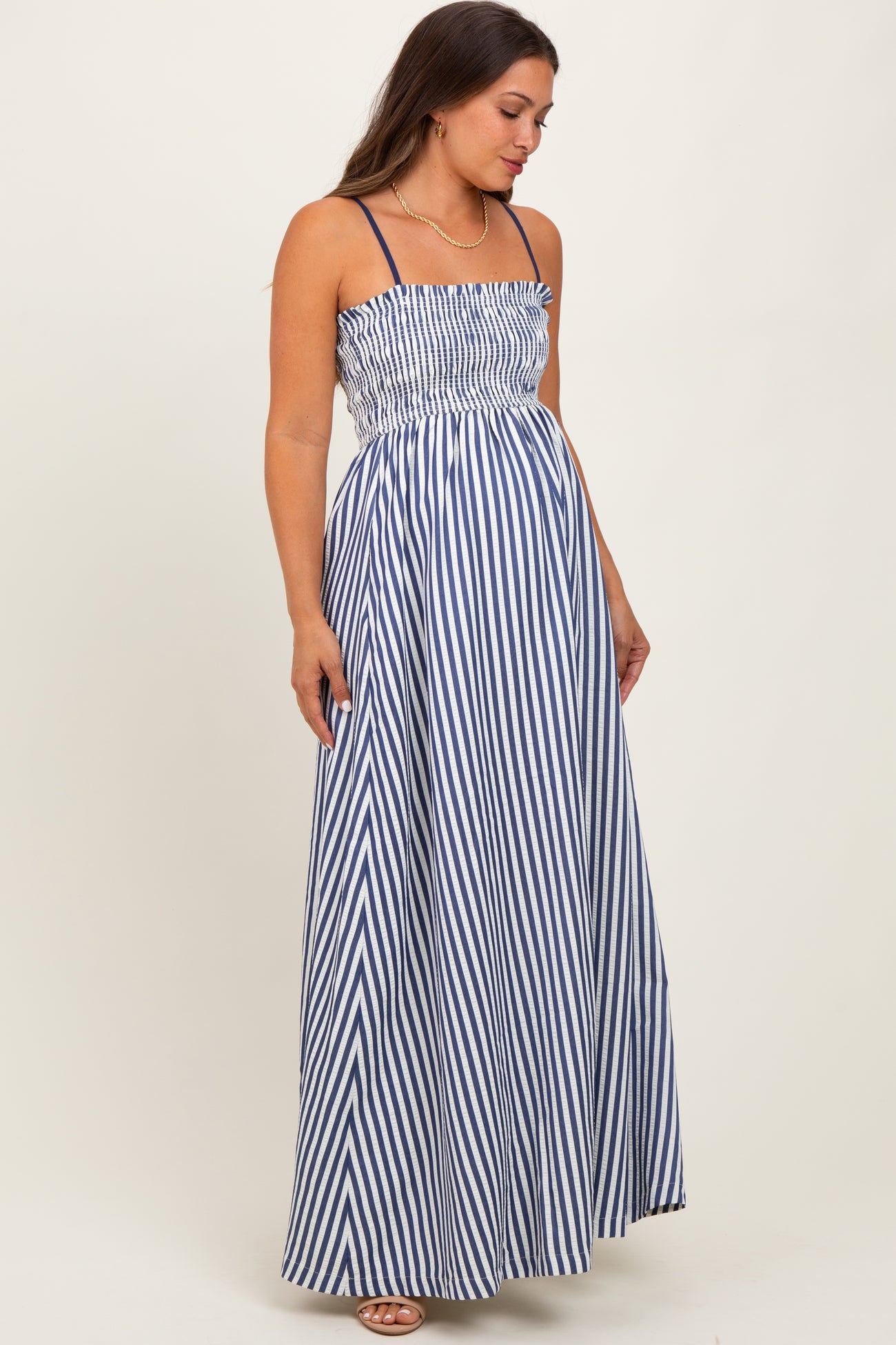 woman wearing a navy and white striped maternity maxi dress with smocked bodice and adjustable straps