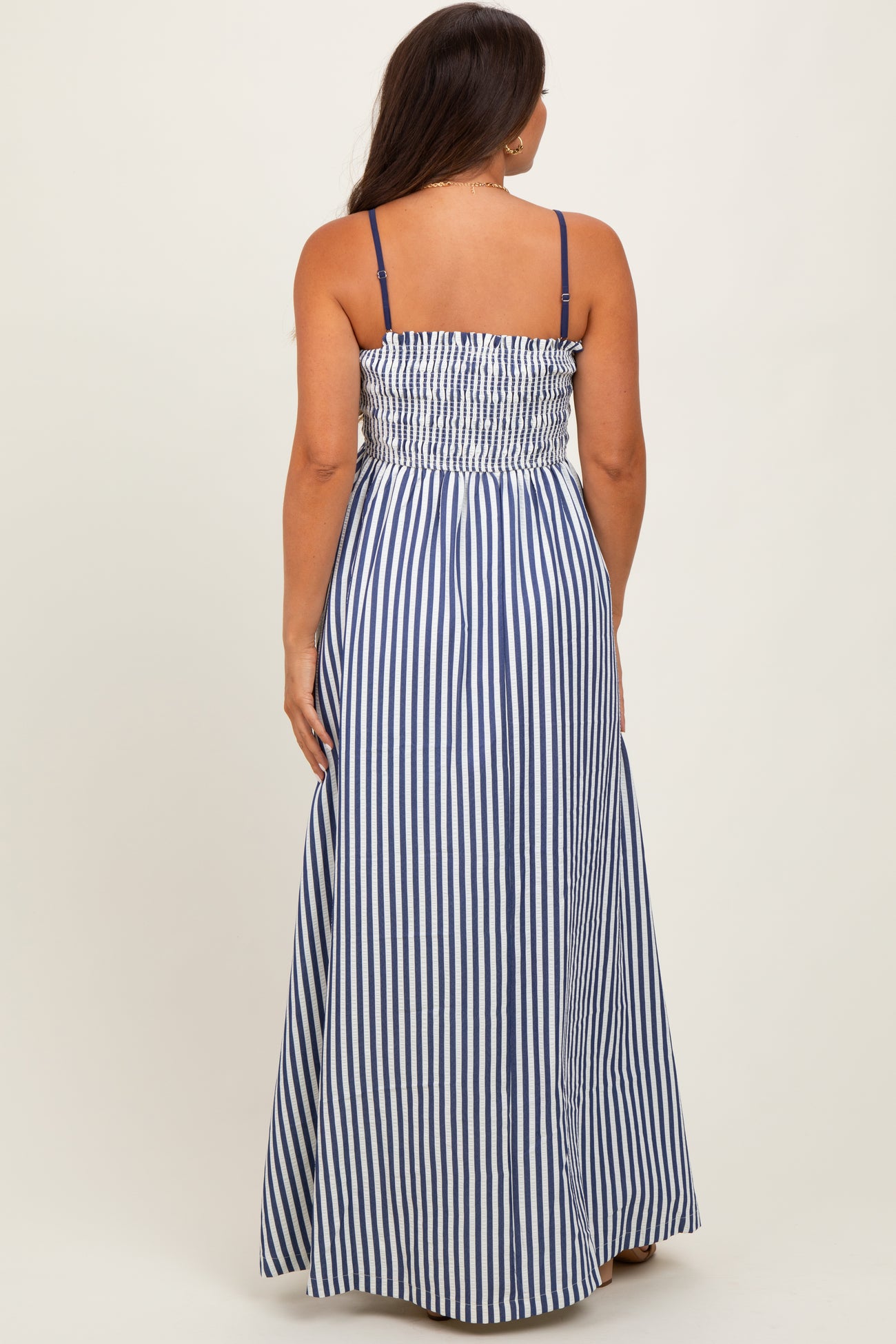 woman wearing a navy and white striped maternity maxi dress with a smocked bodice and adjustable straps