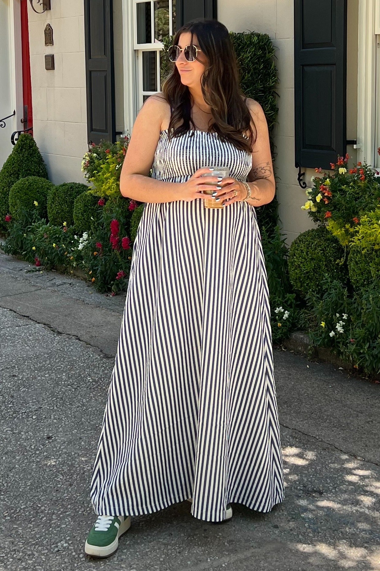 woman wearing a black and white striped maternity maxi dress with a visible baby bump and green sneakers