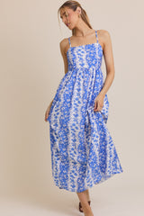woman wearing a blue and white floral maxi dress with spaghetti straps and a fitted bodice