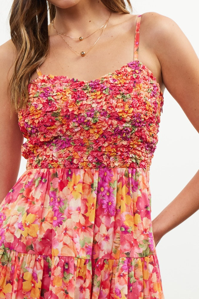 woman wearing a vibrant floral print maxi dress with a ruched bodice and spaghetti straps
