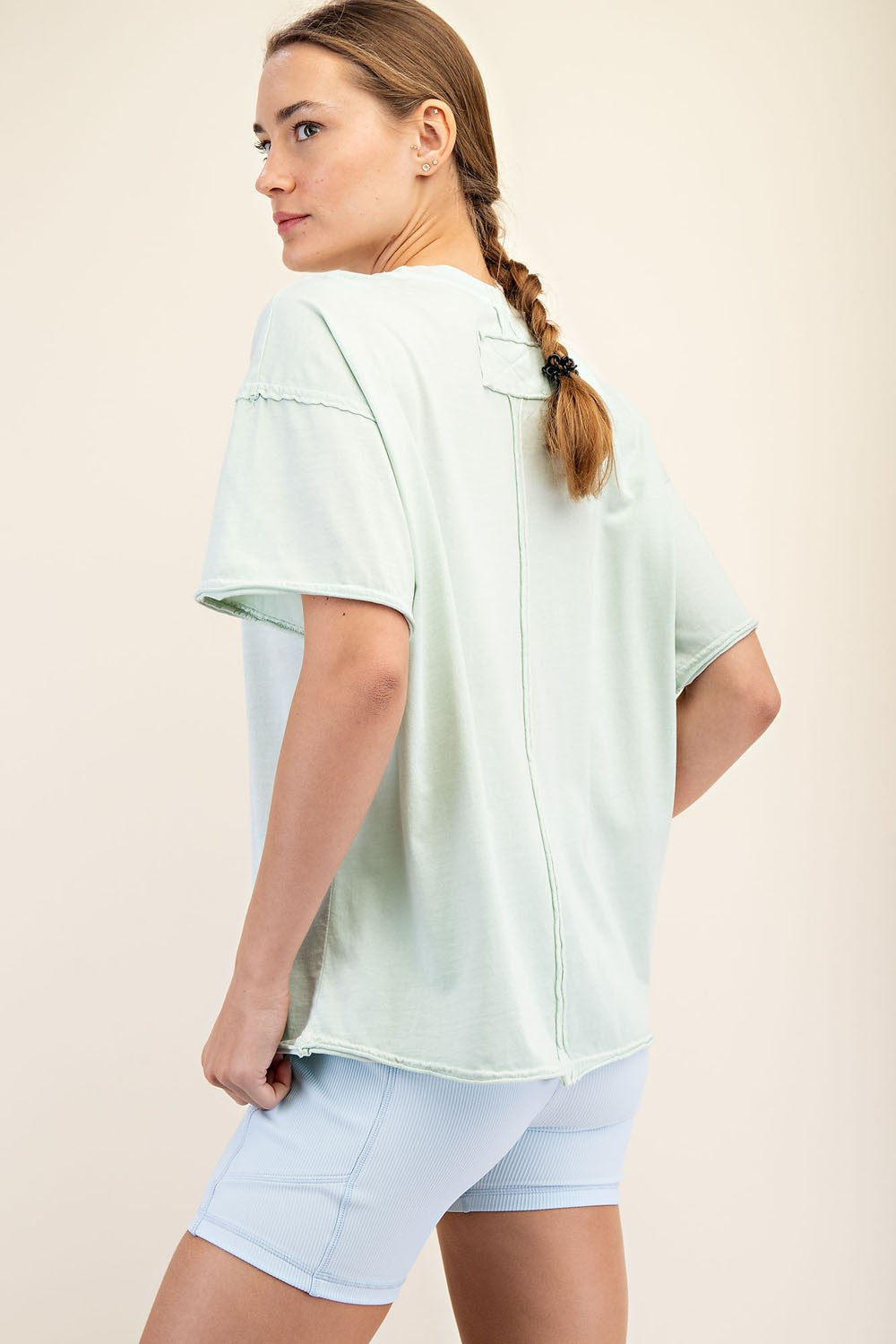 woman wearing a light green oversized t-shirt and light blue ribbed shorts, seen from the back
