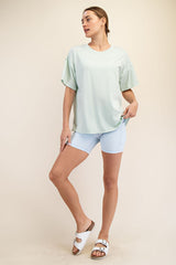 woman wearing a mint green oversized t-shirt and light blue bike shorts, styled with white slide sandals