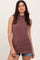 woman wearing a mauve sleeveless ribbed knit top with a high neckline and paired with denim shorts