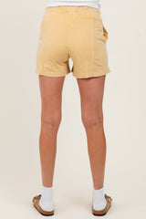 woman wearing light yellow maternity shorts, shown from the back, with a relaxed fit and elastic waistband
