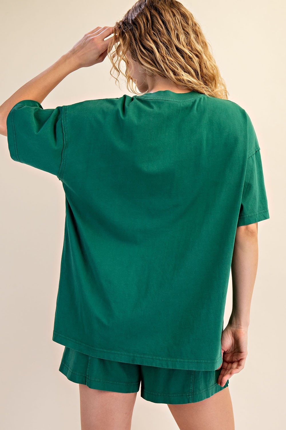 woman wearing a green oversized t-shirt with short sleeves and back view, paired with matching shorts