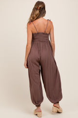 woman wearing a brown maternity jumpsuit with adjustable straps and loose fit, showing a relaxed silhouette from the back