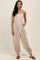 woman wearing a beige strapless jumpsuit with a smocked bodice and side pockets, styled with brown sandals