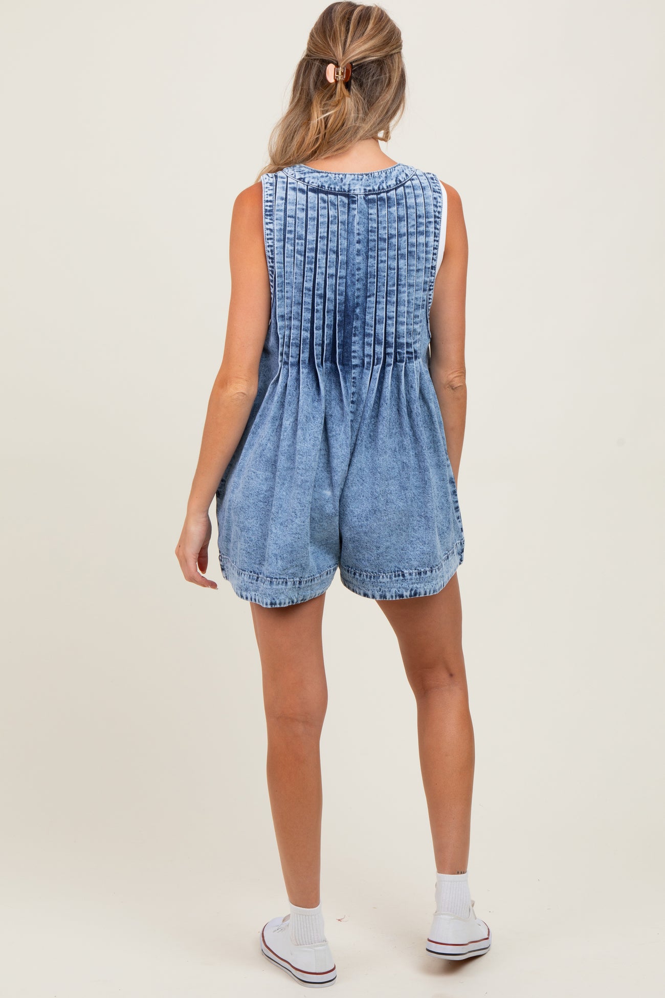woman wearing a denim maternity romper with pleated back detailing, shown from the back