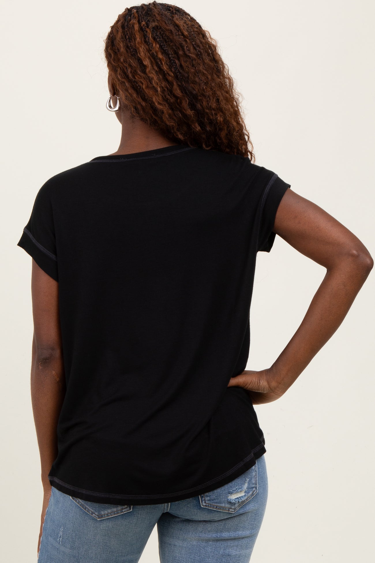 woman wearing a black short sleeve t-shirt, viewed from the back, paired with light blue jeans