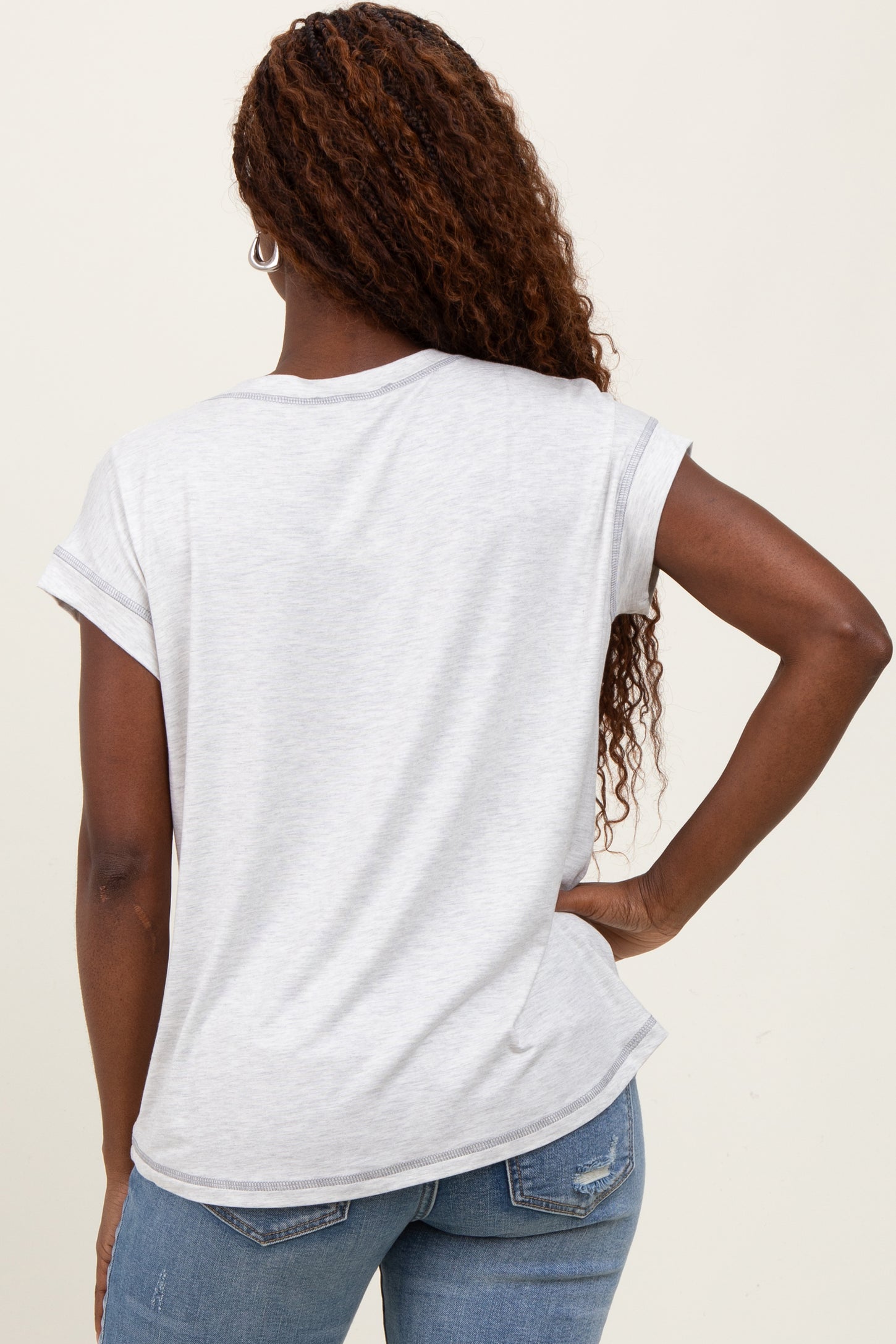 woman wearing a light gray rolled sleeve t-shirt with a loose fit and relaxed style, viewed from the back