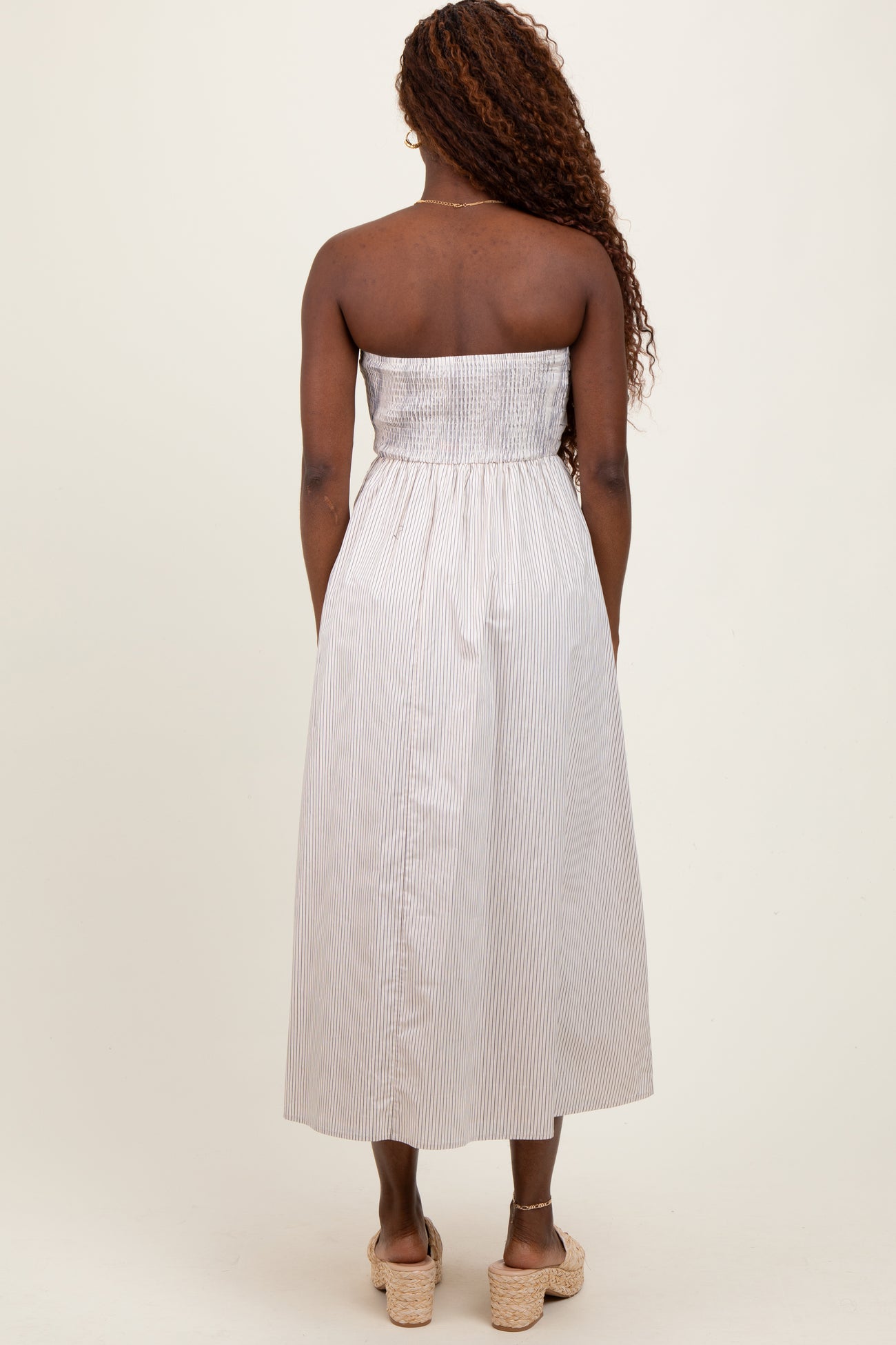 woman wearing a striped strapless midi dress with a smocked bodice and back view, styled with wedges
