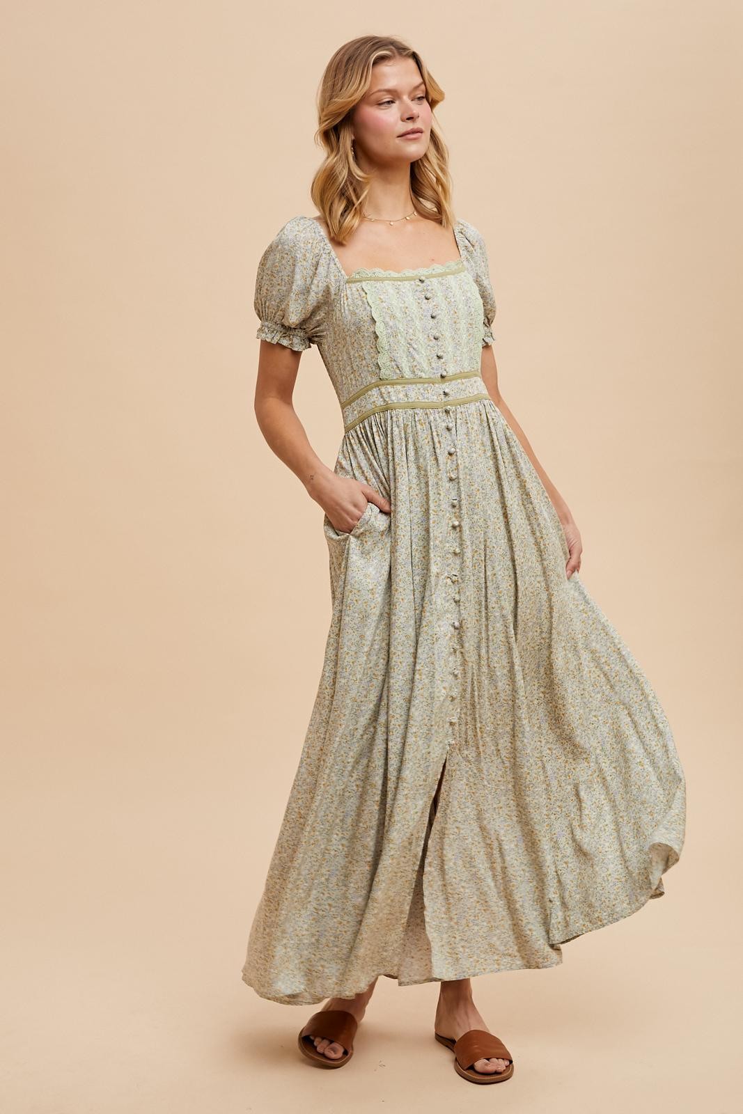 woman wearing a floral print maxi dress with puff sleeves and a square neckline, styled with a belt and pockets
