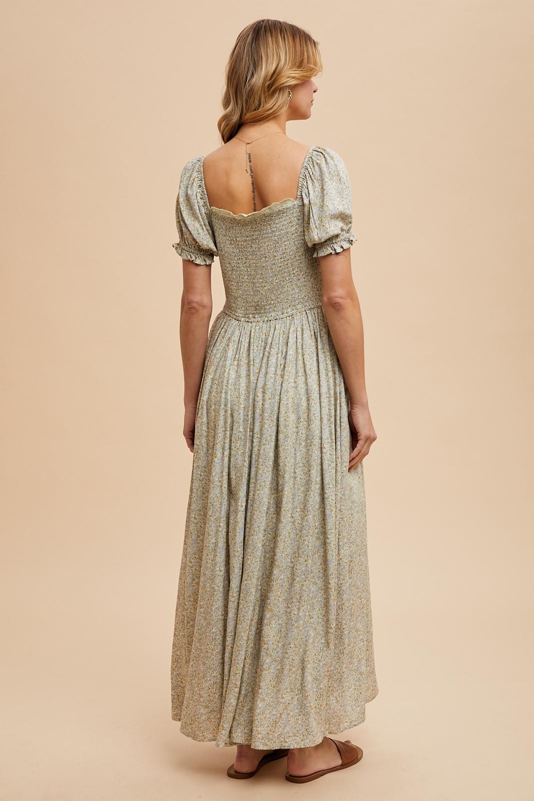 woman wearing a pastel floral long maxi dress with puff sleeves and a fitted bodice, viewed from the back