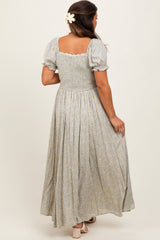 woman wearing a light blue floral maternity maxi dress with puff sleeves, showing a baby bump from the back