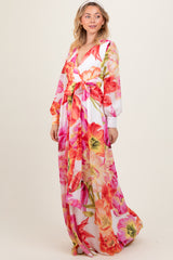 woman wearing a long floral dress with vibrant pink and orange flowers and a tie waist detail