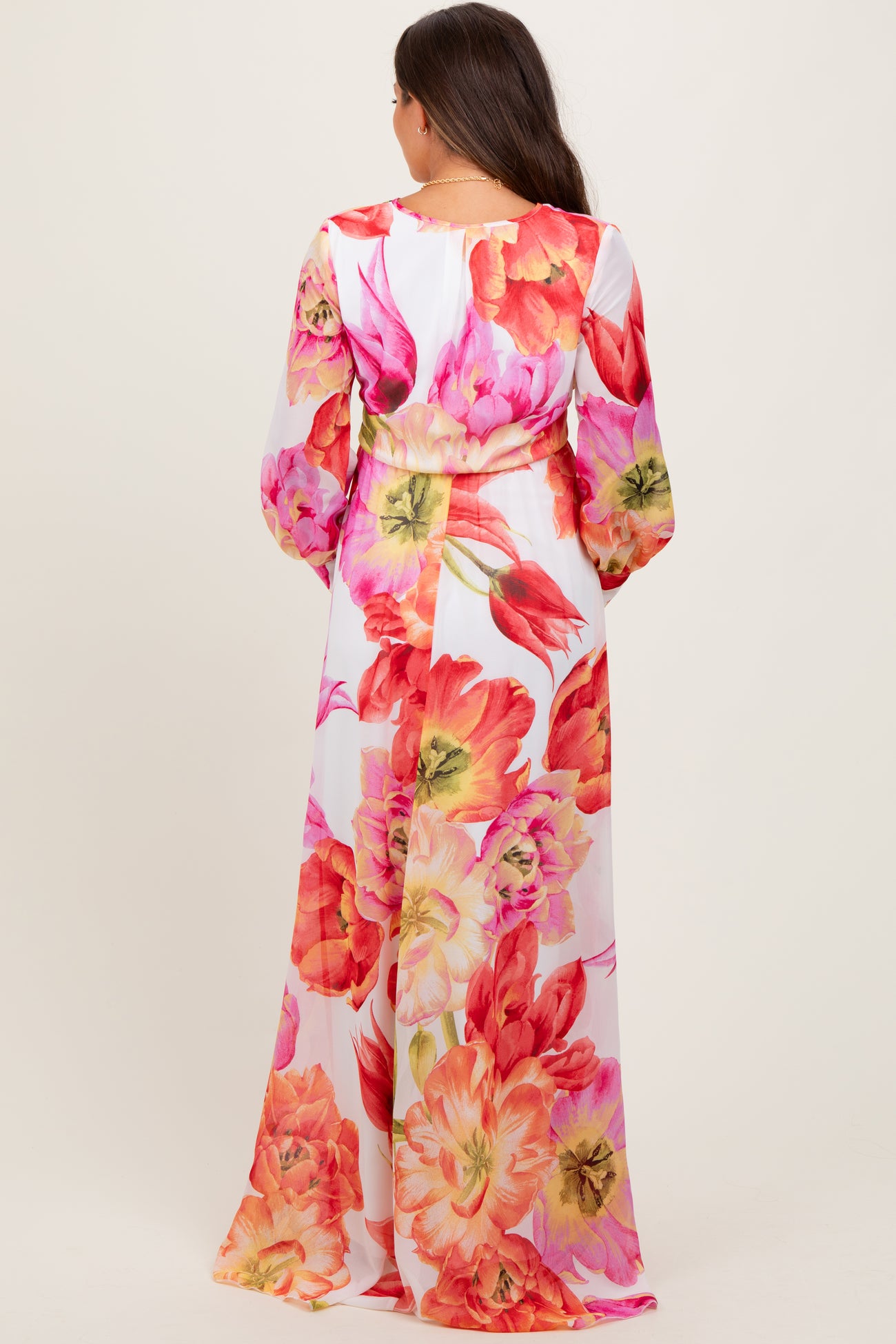 woman wearing a floral long sleeve maternity maxi dress with vibrant pink and orange blossoms