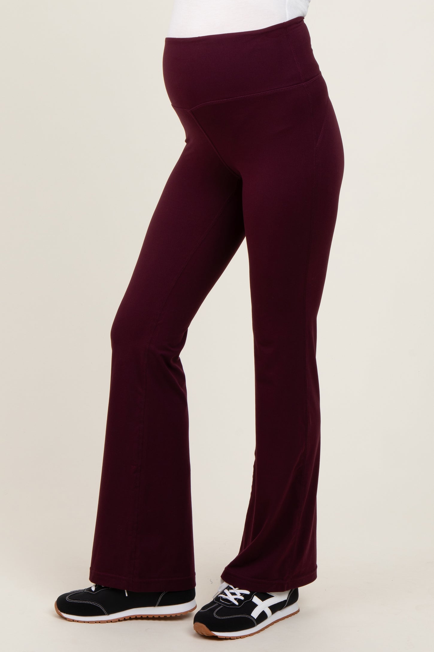 woman wearing burgundy maternity yoga pants with a comfortable waistband and a visible baby bump