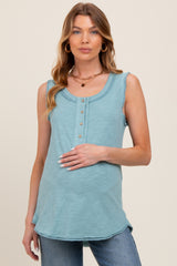 woman wearing a teal maternity tank top with button details and holding her baby bump