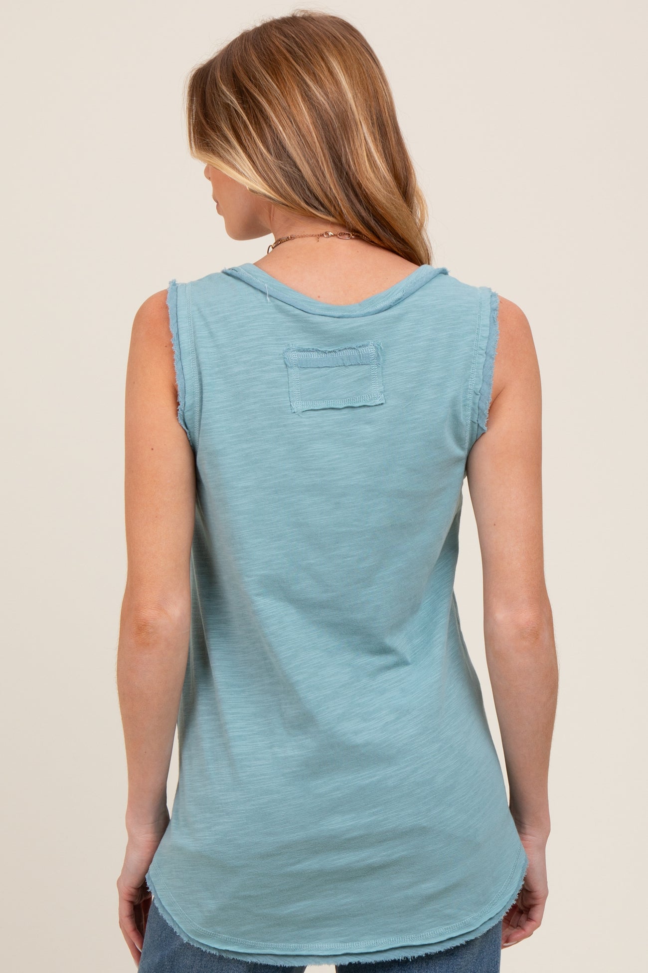 woman wearing a back view of a light blue sleeveless maternity top with a relaxed fit