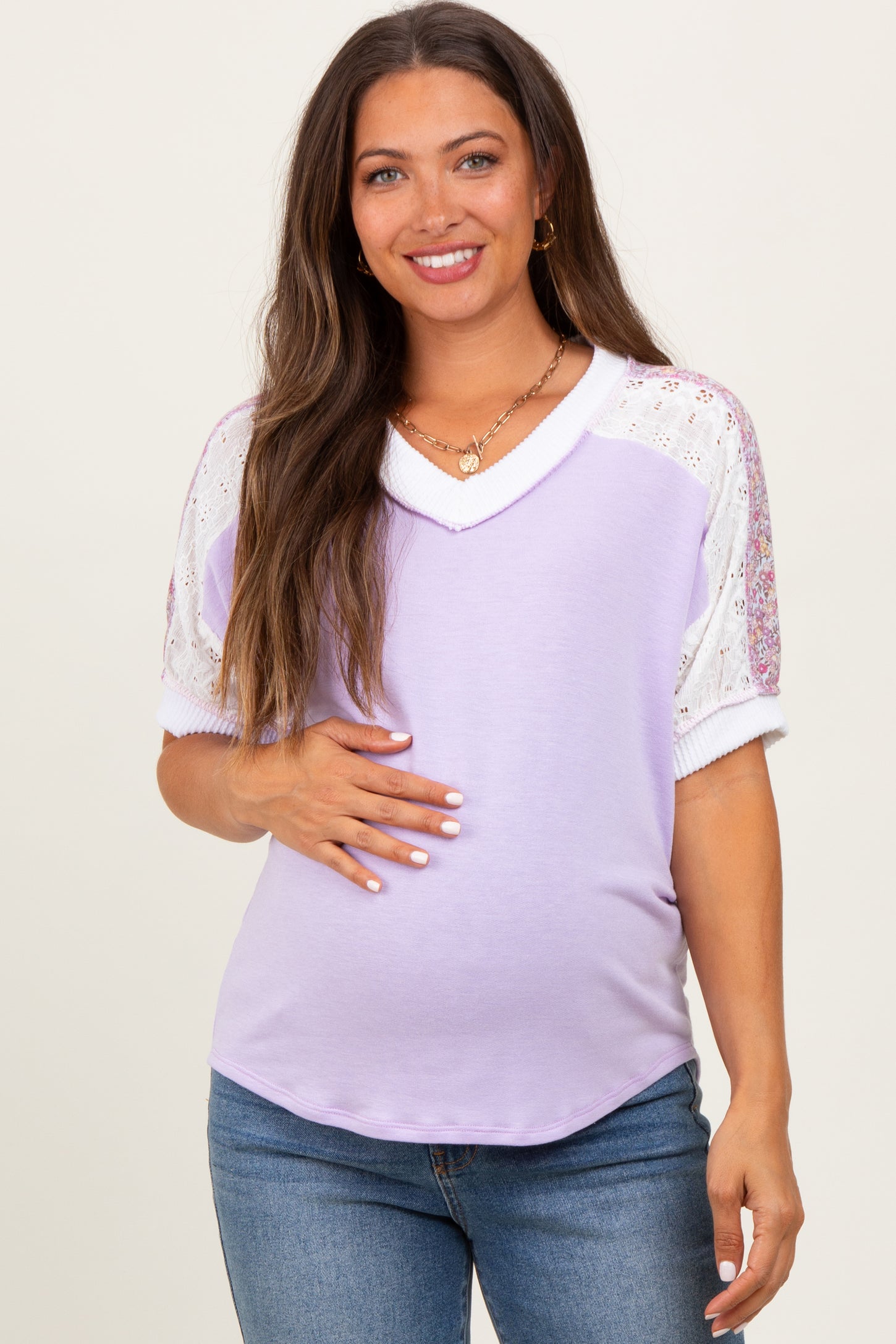 woman wearing a lavender maternity top with lace detail on sleeves and showing her baby bump