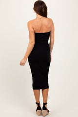 woman wearing a black ribbed midi strapless dress and tan wedge heels, viewed from the back