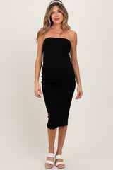 woman wearing a black strapless maternity dress that hugs her baby bump, styled with white sandals