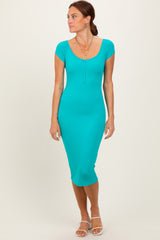 woman wearing a turquoise ribbed midi dress with short sleeves and button detail, styled with white strappy sandals