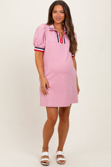woman wearing a light pink maternity dress with puff sleeves and a sporty collar, displaying a baby bump